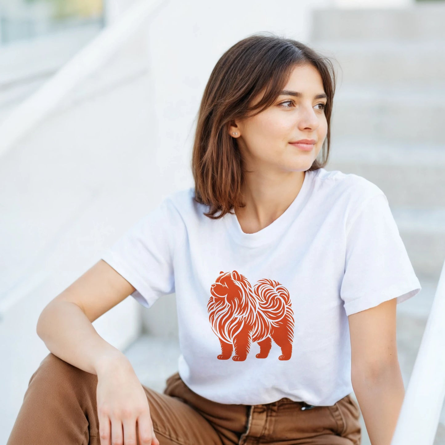 Woman wearing a white t-shirt with an orange chow chow dog design, sitting on steps.