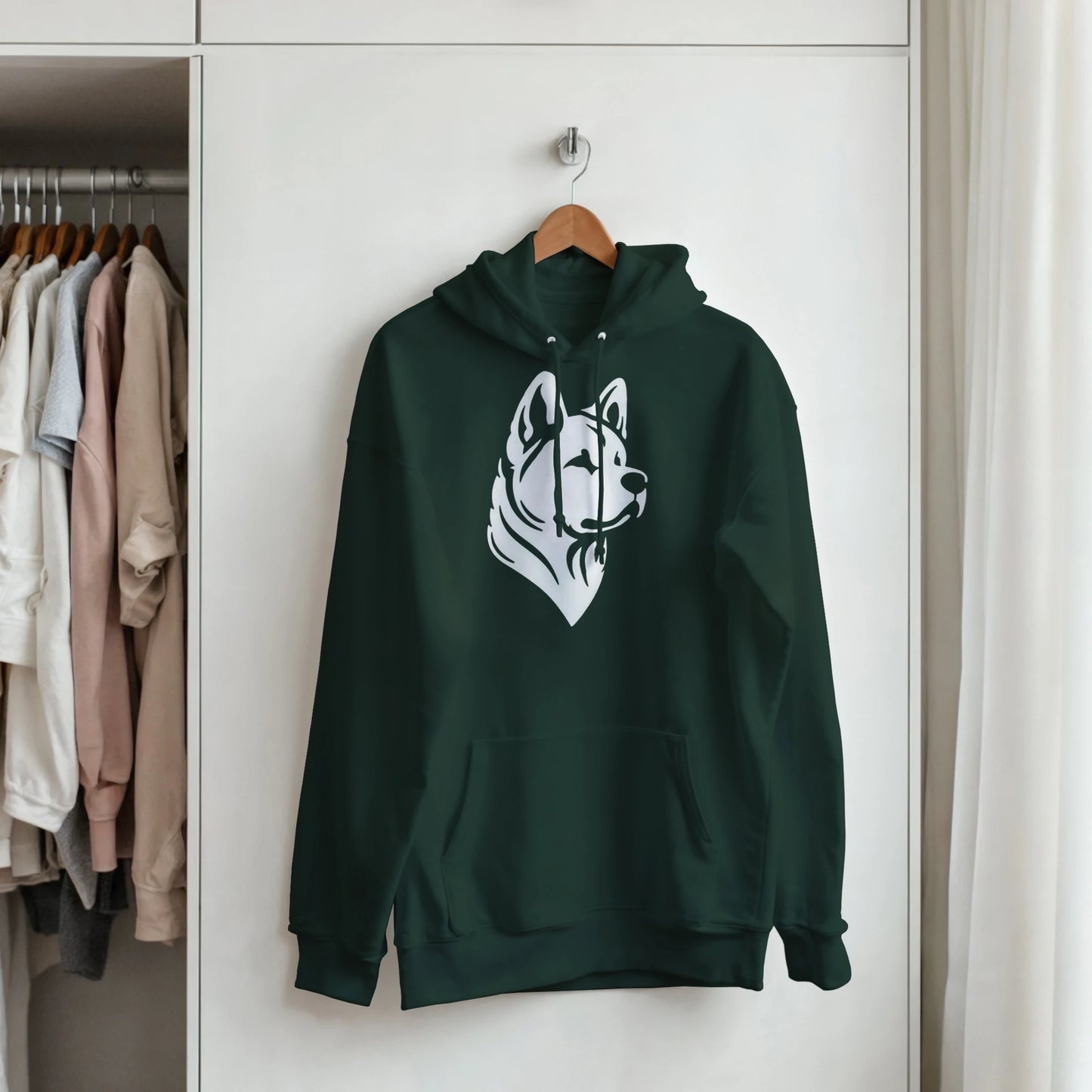 Green hoodie with a dog graphic on a hanger in a wardrobe.