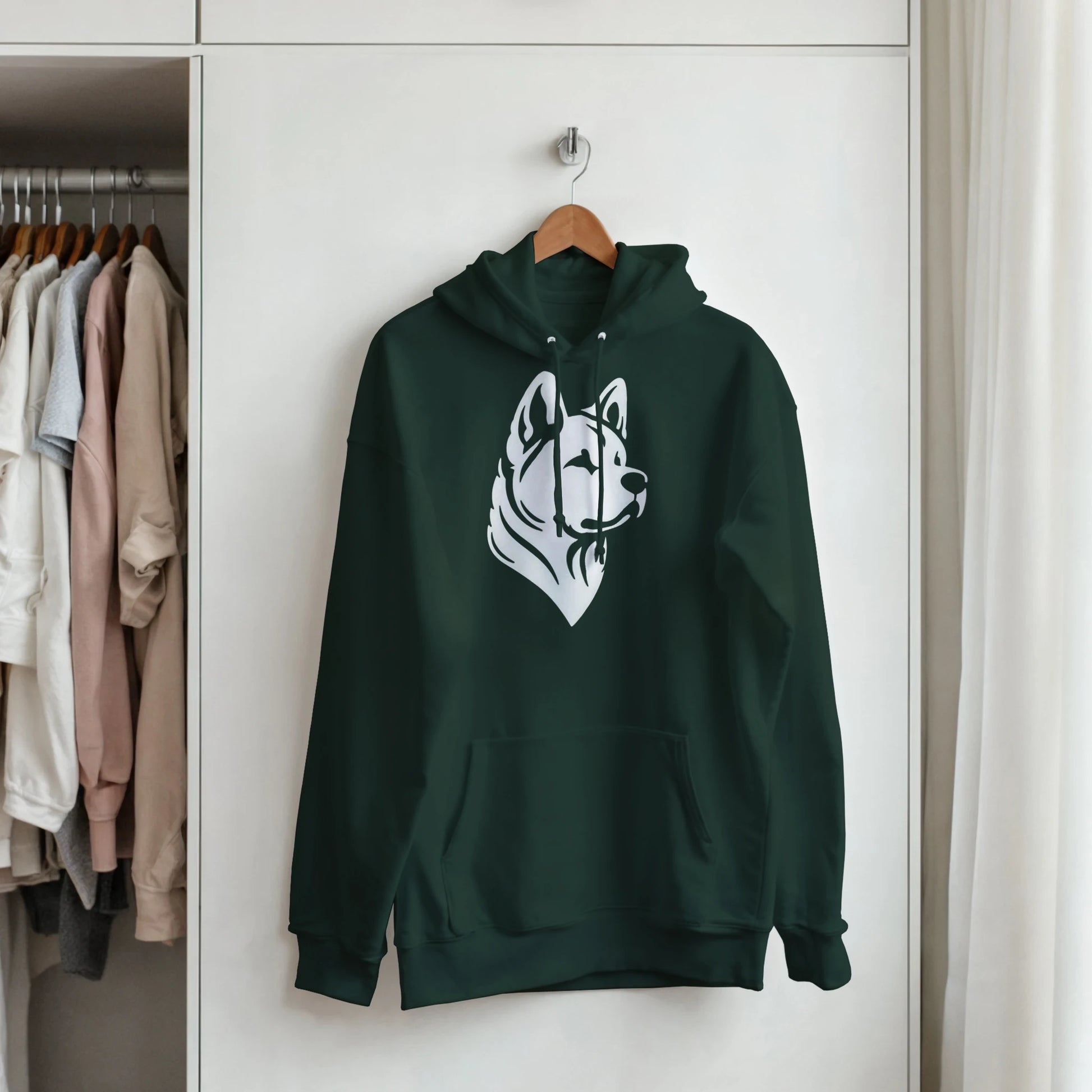 Green hoodie with a dog graphic on a hanger in a wardrobe.