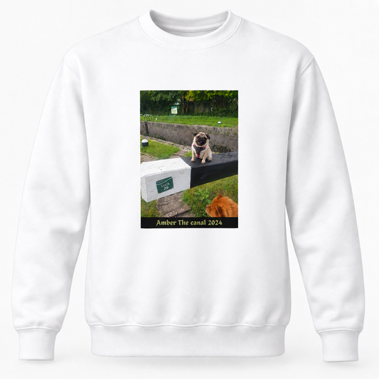 A white crewneck sweatshirt featuring a rectangular graphic print on the front. The print shows a pug sitting on a stone wall next to a white cooler with the text 'Amber The canal 2024' below it.