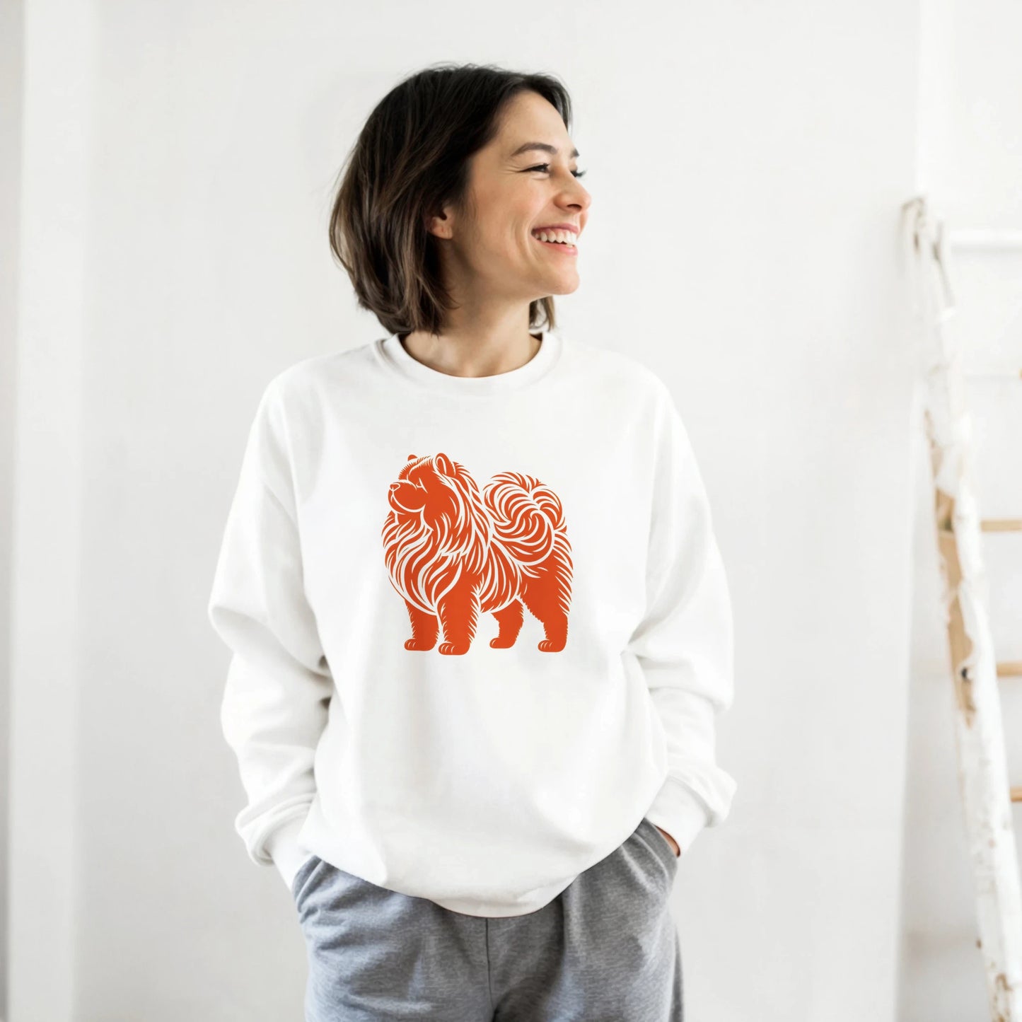 Person wearing a white sweatshirt with an orange chow chow design on a plain background