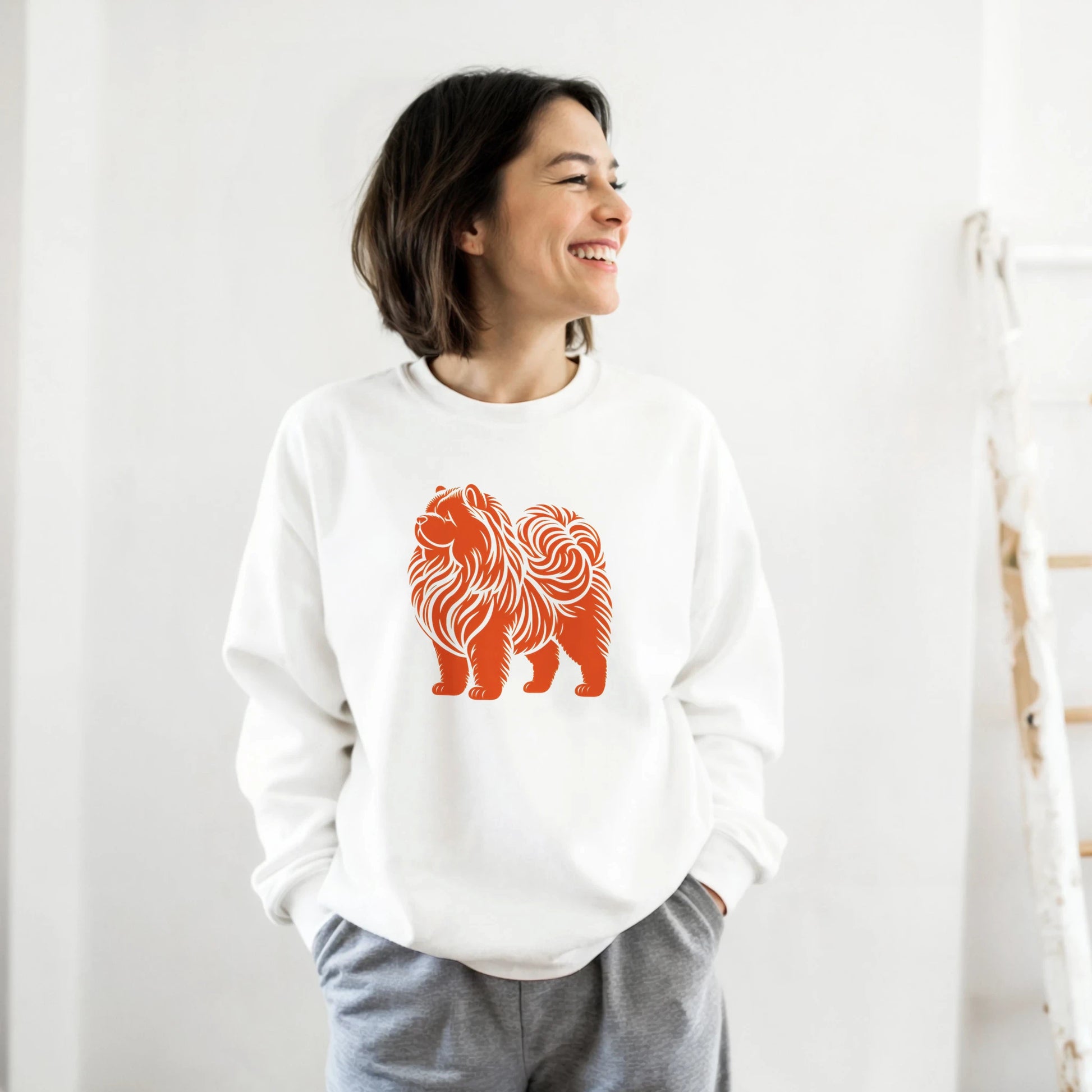 Person wearing a white sweatshirt with an orange chow chow design on a plain background
